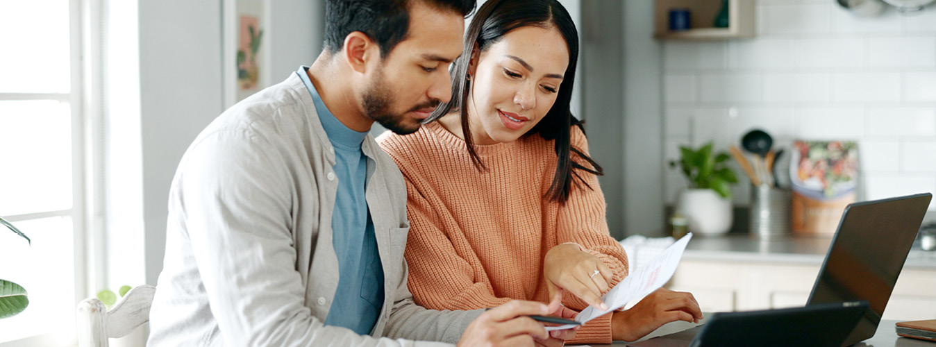 Kitchen, couple and discussion with document for finance, track expenses and laptop for budget goal. Conversation, man and woman with tax paper for checking, mortgage review or handle savings at home