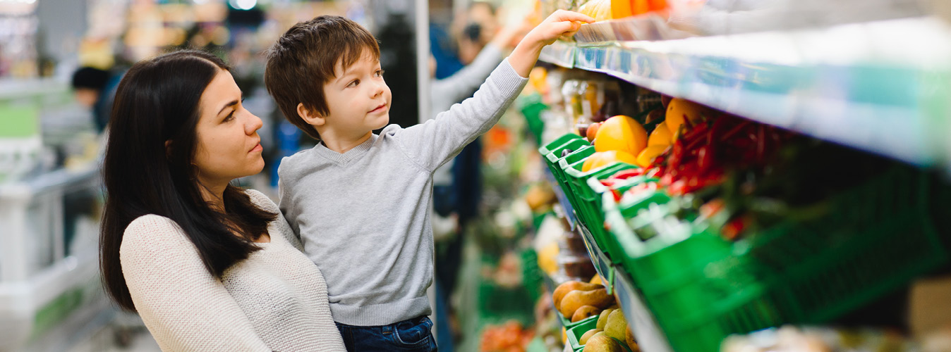 Young mother with her little baby boy at the supermarket. Healthy eating concept
