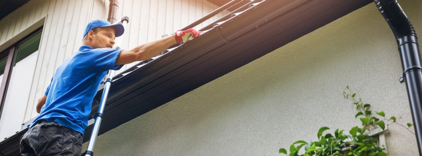 Man cleaning gutters on ladder