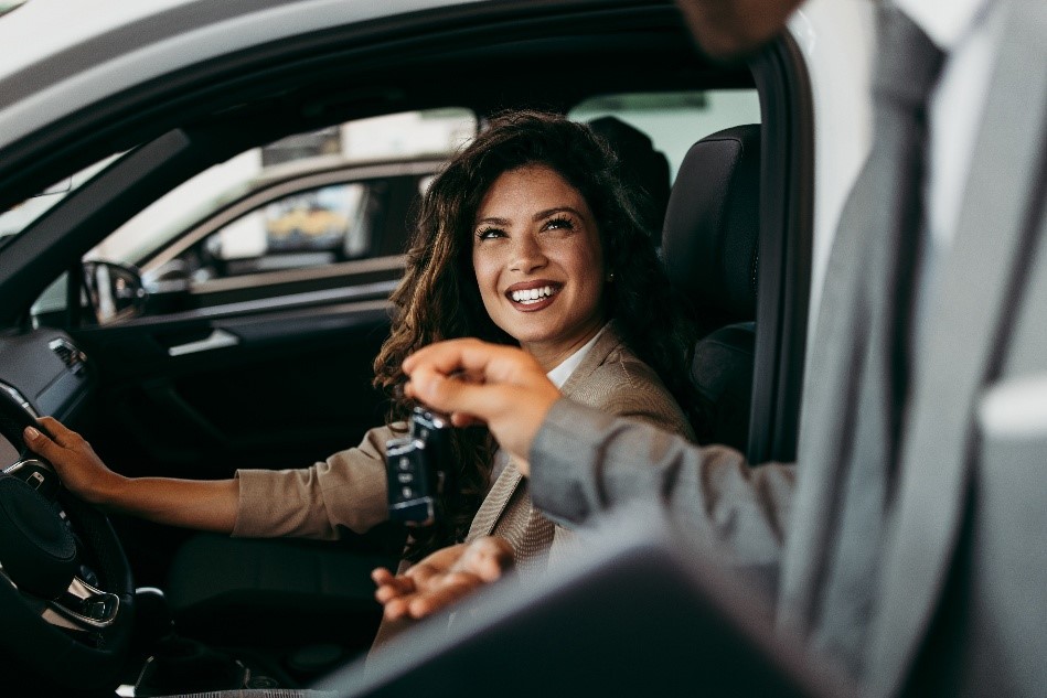 Woman sitting in car while man hands her car keys