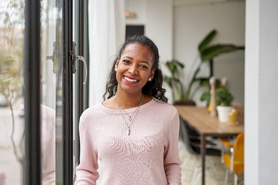 Woman standing in hallway next to a glass door smiling