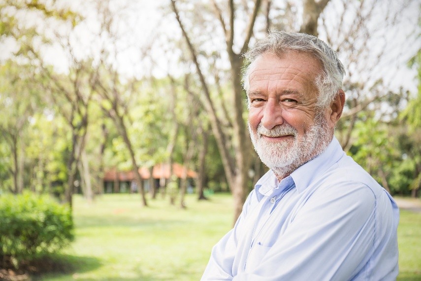 Man standing in front of trees smiling
